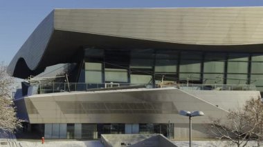Karlı Münih, Almanya. BMW Welt, BMW Kulesi ve karargah parlak kış güneşi altında parlıyor. Modern mimari şehir zarafetiyle buluşuyor, karla kaplı sokaklar ve berrak mavi gökyüzü. Kış şehri