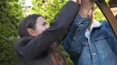 Erkek ve kadın, küçük işletme düğün dekoratörleri, açık hava bahçe töreni için ahşap bir çiçek kemeri kurun. Birlikte çalışıyorlar, güzel bir ortam yaratmak için detaylara çok dikkat ediyorlar.. 