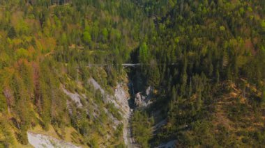 Luftaufnahme Schurpfen Wasserfall. Eğri şelale Schurpfen 'in hava manzarası ve Lenggries' deki Sylvensteinspeicher yakınlarında orman dağı ve kanyonla dolu bir köprü. İnsansız hava aracı görüntüsü düşüyor ve köprü. 