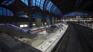 31 Aralık 2023. Hamburg, Almanya. Hamburg Hauptbahnhof, merkez istasyonunda hareketli bir akşam sahnesi. Kalabalık gezginler, aydınlanmış platformlar ve trenler şehirsel bağlantı ve hareketlilik merkezi.. 