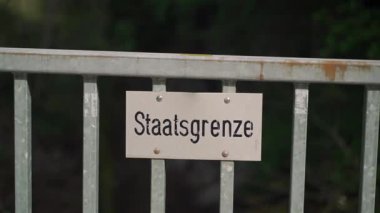 Schilder Grenze zwischen Deutschland ve Oesterreich. Tafel Staatsgrenze. Politische Grenze. Schild Grenzlinie zwischen Staatsgebieten. Çit Almanya 'da devlet sınırını işaret ediyor. Almanca Kenarlık Yazısı