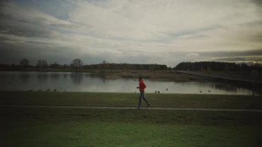 Almanya 'da parkta göl boyunca koşan bir adam. Atletik genç insan doğada koşar. Sağlıklı bir yaşam tarzı. Erkek, Münih 'teki bir şehir parkında gölet kenarında koşuyor. Göl kenarındaki patikada koşan adam.. 