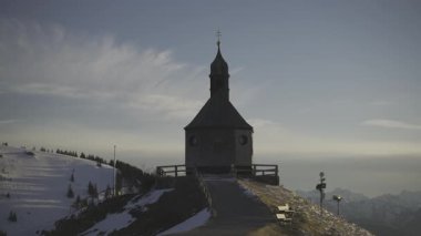 Kapelle Heilig Kreuz, Rottach-Egern, Bavyera, Almanya 'da Tegernsee' de kış günbatımında. Karla kaplı Alp manzaralı güzel bir şapel. Bavyera Alpleri 'nde huzurlu bir atmosferi ve dingin doğası var.