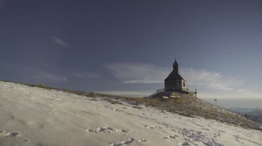 Kapelle Heilig Kreuz, Rottach-Egern, Bavyera, Almanya 'da kışın gün batımında Bayerischen Tegernsee' de. Bavyera Alpleri 'nde karla kaplı dağ manzaraları ve dingin doğa ile çevrili manzara şapeli.. 