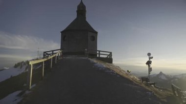 Kapelle Heilig Kreuz, Rottach-Egern, Bavyera, Almanya 'da kışın gün batımında Bayerischen Tegernsee' de. Bavyera Alpleri 'nde karla kaplı dağ manzaraları ve dingin doğa ile çevrili manzara şapeli.. 