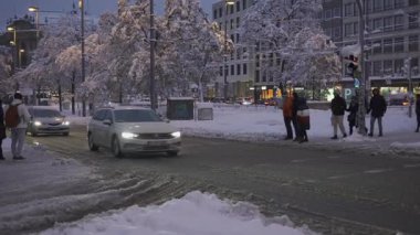 20 Aralık 2024. Münih, Almanya. Muenchen 'de karlı bir akşam, yoğun kar yağışı sokakları, arabaları ve ağaçları kaplıyor. Şehir ışıkları parlıyor, trafik yavaş ilerliyor. Karlsplatz rekor kıran karla kaplıdır.. 