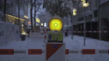 Almanya 'nın Münih kentindeki karlı cadde yoğun kar yağışı nedeniyle kapatıldı. Yayaların yağan kardan korunması için uyarı ışığı ve uyarı bandı tehlikeli bölgeye işaret ediyor. Kış güvenlik önlemleri alındı. 