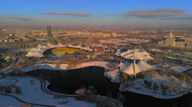 Olympiastadion im Olympiapark Munchen, Deutschland Luftaufnahme im Winter bei verschnemaddesi, sonnigem Wetter. Olimpiyat Parkı Münih 'teki Olimpiyat Stadyumu, Almanya' da kış aylarında hava durumu güneşli.. 