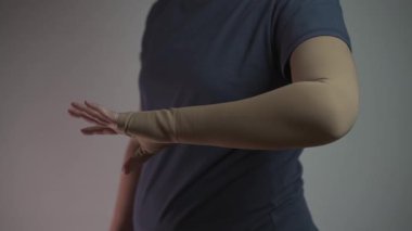 Stüdyodaki kadın kol desteği için tıbbi baskı kolu gösteriyor. Tromboz, lenf kanseri ve dolaşım sorunları için tasarlanmış. İyileşmeye yardımcı olur, şişkinliği azaltır ve kan akışını iyileştirir.. 