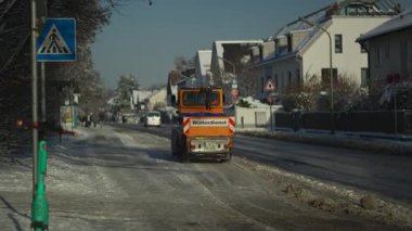 Turuncu makine kar yağdıktan sonra Münih, Almanya 'da kaldırım ve bisiklet yolundan hızla kovayla kar kürüyor. Winterdienst, Almanya 'da. Yollardan kar temizleyen traktör.. 