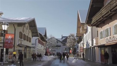 25 Aralık 2024. Garmisch-Partenkirchen, Almanya. Güneşli bir kış günü, karlı sokaklar, kapalı dükkanlar, yayalar, gezinen insanlar olan huzurlu bir kasaba. Garmisch Partenkirchen şehir merkezinde.