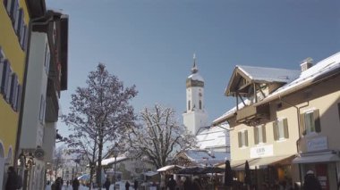 25 Aralık 2024. Garmisch-Partenkirchen, Almanya. Güneşli bir kış günü, karlı sokaklar, kapalı dükkanlar, yayalar, gezinen insanlar olan huzurlu bir kasaba. Garmisch Partenkirchen şehir merkezinde.