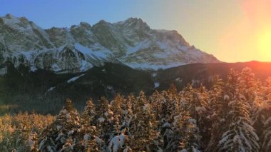 Alman Bavyera Alpleri 'ndeki kar kaplı ağaç tepelerinde nefes kesen hava manzarası, Zugspitze kitsif sergileniyor. Zugspitze Gipfel Wetterstein Dağları 'nın en yüksek zirvesi ve Almanya' nın en yüksek dağı. 