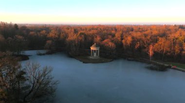 Apollotempel Muenchen im Schlosspark Nymphenburg, Alman Luftbildaufnahme. Almanya 'da Badenburger See ve Apollotempel, sonbaharda Münih hava manzarası gün batımında. Apollotemple Park 'ta Nymphenburg. 