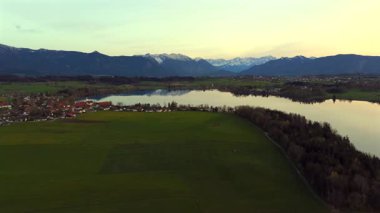 Oberbayern bei Sonnenuntergang 'dan Der Riegsee. Murnau, Bavyera, Almanya, Avrupa yakınlarındaki Riegsee Gölü 'nün havadan görüntüsü. Baharda gün batımında arka planda Ammergauer Alpen. Turizm Bölgesi Das Blaue Arazisi. 