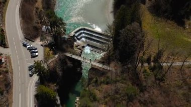 Lechfall, Fussen, Bavyera 'da çarpıcı bir şelale, yüksek açılı bir drone atışından yakalanmış. Manzaralı köprü, kristal berraklığında nehir ve resimli manzara onu mükemmel bir seyahat ve fotoğraf noktası yapıyor.