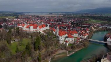 Fussen 'in kırmızı çatıları, Gotik mimarisi ve tarihi simgeleri olan eski kasabasının insansız hava aracı görüntüleri. Lech Nehri, Bavyera 'nın zengin kültürel mirasını ön plana çıkararak, pitoresk bir manzara boyunca esiyor.. 