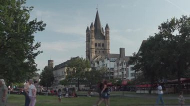 20 Temmuz 2024. Köln, Almanya. Gross Sankt Martin am Fischmarkt in Koeln, Deutschland im Sommer Blick vom Rheinufer. Büyük St. Martin Kilisesi, Köln. İnsanlar rıhtımda yürüyor ve dinleniyor.. 