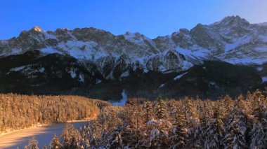 Alman Bavyera Alpleri 'ndeki kar kaplı ağaç tepelerinde nefes kesen hava manzarası, Zugspitze kitsif sergileniyor. Zugspitze Gipfel Wetterstein Dağları 'nın en yüksek zirvesi ve Almanya' nın en yüksek dağı. 
