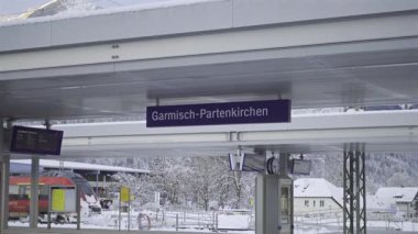 Karlı Bavyera Alplerinde manzaralı tren yolculuğu. Garmisch-Partenkirchen istasyonu bölgesel ve şehirlerarası trenleri birbirine bağlıyor ve yolculara çarpıcı dağ manzaraları ve gerçek kış titreşimleri sunuyor. Bahnhof. 