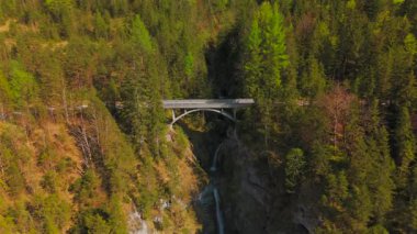 Luftaufnahme Schurpfen Wasserfall. Eğri şelale Schurpfen 'in hava manzarası ve Lenggries' deki Sylvensteinspeicher yakınlarında orman dağı ve kanyonla dolu bir köprü. İnsansız hava aracı görüntüsü düşüyor ve köprü. 