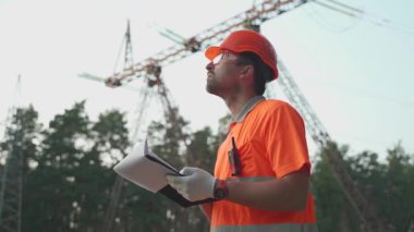 PPE 'deki mühendis alandaki yüksek voltajlı elektrik hatlarını inceleyerek güvenlik uyumunu ve altyapı bütünlüğünü sağlıyor. İletişim kulelerinin ve elektrik şebekelerinin teknik kontrolü devam ediyor..