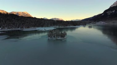 Ludwigsinsel, Heissenbuchel 'in Garmisch-Partenkirchen, Bavyera, Almanya yakınlarındaki donmuş Eibsee Gölü üzerindeki hava manzarası. Karla kaplı ağaçlar ve buzlu sularla huzurlu bir kış sabahı büyülü bir manzara yaratır.. 