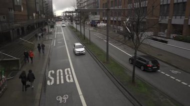 Hamburg, Deutschland. Bulutlu bir günde Hamburg, Almanya 'da şehir caddesi. Yayalar modern ofis binalarının yanında kaldırımlar boyunca yürürler. Otomobiller ve otobüs şeridi, şehrin organize altyapısını vurguluyor. 