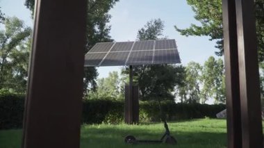 Güneş panellerinin yakınına park etmiş elektrikli scooter, yeşil teknolojiyi, yenilenebilir enerjiyi, çevre dostu ulaşımı, sürdürülebilir hareketliliği, temiz enerji çözümlerini ve sıfır emisyonlu geleceği simgeliyor.