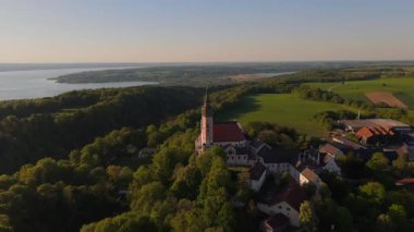 Kloster Andechs 'in ve Ammersee Gölü, Bavyera, Almanya' daki Holy Mountain 'daki kutsal kilisenin insansız hava aracı videosu. Manastır, doğa ve Münih yakınlarındaki kırsal manzaranın günbatımı manzarası