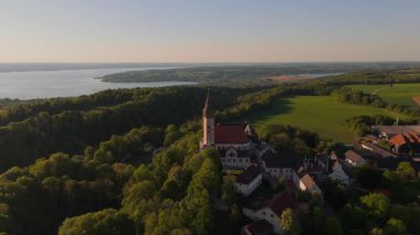 Luftaufnahme Kloster Andechs bei Muuenchen, Bayern. Drohnenvideo Wallfahrtskirche auf dem Heiligen Berg am Ammersee mit Landschaft, See und Sonnenuntergang. Andech 'leri Burg. Braustuberl des Klosters. 