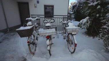 Alman ormanındaki küçük bir apartmanın önünde karla kaplı üç bisiklet park etmiş. Sepetler dolusu kar, huzurlu kış manzarası, kırsal yaşam tarzı, Avrupa 'nın banliyölerinde sakin karlı bir gün. 