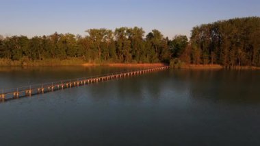 Almanya 'nın Bavyera eyaletindeki Woerthsee Gölü' nde yer alan Mausinsel 'e uzanan 260 metre uzunluğundaki tahta geçit köprüsünün havadan görünüşü. Orman, sakin su ve manzaralı yaz güzelliği ile çevrili