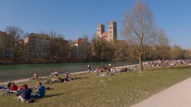 27 Nisan 2022. Münih, Almanya. Menschenmengen geniessen die ersten warmen Tage an der Isar bei St. Maximilian. Radfahrer, Familien und Freunde beleben das gruene Herz Muenchens. 