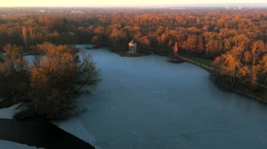 Apollotempel Muenchen im Schlosspark Nymphenburg, Alman Luftbildaufnahme. Almanya 'da Badenburger See ve Apollotempel, sonbaharda Münih hava manzarası gün batımında. Apollotemple Park 'ta Nymphenburg. 
