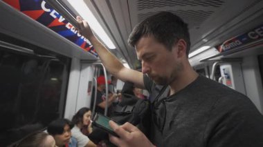 İtalya 'da Roma metrosundaki erkek yolcu yazın kalabalık bir metro treninde akıllı telefon kullanıyor. Erkek, Roma 'da tren vagonunda seyahat ederken telefon kullanıyor. Roma 'da toplu taşıma teması