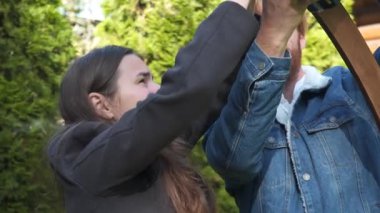 Erkek ve kadın, küçük işletme düğün dekoratörleri, açık hava bahçe töreni için ahşap bir çiçek kemeri kurun. Birlikte çalışıyorlar, güzel bir ortam yaratmak için detaylara çok dikkat ediyorlar.. 