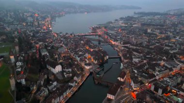 Stadtbild von Luzern Luftaufnahme, Schweiz bei Nacht mit Stadtlichtern, nebligem Wetter. Luftbild vom Fluss Reuss und allen bekannten Bruecken am Abend. Gece Lucerne şehir merkezinin havadan görünüşü