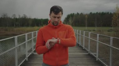 Koşucu spor saatine bakıyor. Atletik koşucu fitness izleyicisi üzerinde çalışmaya başladı. İz sürme ve aktif yaşam tarzı kavramı. Spor, koşu, sağlıklı yaşam tarzı. GPS konumu veya nabzı kontrol ediliyor. 