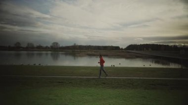 Almanya 'da parkta göl boyunca koşan bir adam. Atletik genç insan doğada koşar. Sağlıklı bir yaşam tarzı. Erkek, Münih 'teki bir şehir parkında gölet kenarında koşuyor. Göl kenarındaki patikada koşan adam.. 