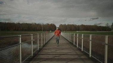 Erkek koşucu köprüde antrenmanı bitirir. Uzaklık ve zamanı kontrol eder. Sakinleşiyor, derin bir nefes alıyor ve müziğini kapatıyor. Spor kıyafetleri içinde, temiz havanın tadını çıkarıyor.. 