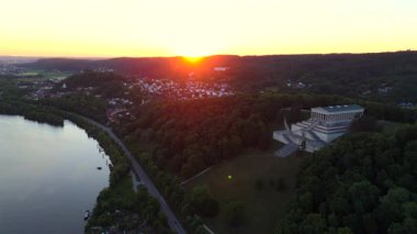 Walhalla bei Donaustauf im Sonnenuntergang. Luftaufnahme des klassizistischen Tempels auf dem Braeuberg bei Regensburg. Die Donau fliesst zu Fuessen, umgeben von goldener Abendstimmung. 