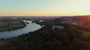 Donaustauf, Bavyera 'da gün batımında Walhalla. Drone görüntüleri, Almanya 'nın Regensburg yakınlarındaki tepelerin üzerinden panoramik manzaralı ve yumuşak akşam ışığında Tuna Nehri üzerindeki mermer tapınağı yakalıyor.