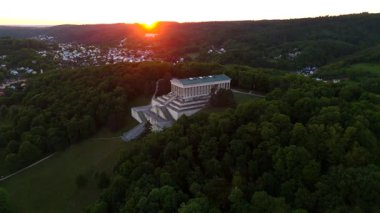 Almanya, Regensburg yakınlarındaki Braeuberg tepesindeki Walhalla anıtının günbatımı hava manzarası. Bu neoklasik tapınak Tuna Nehri 'ne bakıyor. Bavyera manzarası üzerinde altın saat ışığı parlıyor.. 