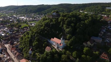 Donaustauf, Bavyera 'daki Aschenbuegl Dağı' nın eteğindeki St. Michael Kilisesi 'nin havadan görünüşü. Barok kilisesi, ortaçağ kulesi ve yakınlardaki kale kalıntıları manzaralı tarihi bir manzara oluşturur.. 