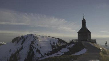 Kapelle Heilig Kreuz, Rottach-Egern, Bavyera, Almanya 'da kışın gün batımında Bayerischen Tegernsee' de. Bavyera Alpleri 'nde karla kaplı dağ manzaraları ve dingin doğa ile çevrili manzara şapeli.. 