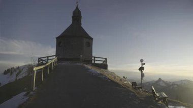 Kapelle Heilig Kreuz, Rottach-Egern, Bavyera, Almanya 'da Tegernsee' de kış günbatımında. Karla kaplı Alp manzaralı güzel bir şapel. Bavyera Alpleri 'nde huzurlu bir atmosferi ve dingin doğası var.