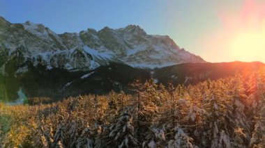 Alman Bavyera Alpleri 'ndeki kar kaplı ağaç tepelerinde nefes kesen hava manzarası, Zugspitze kitsif sergileniyor. Zugspitze Gipfel Wetterstein Dağları 'nın en yüksek zirvesi ve Almanya' nın en yüksek dağı. 