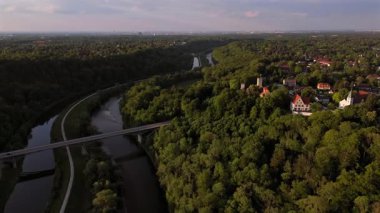 Die Burg Gruenwald thront auf einem Huegel uber der Isar und dem Kanal suedlich von Muenchen. Zu sehen ist die historische Bogenbruecke Gruenwalder Isarbruecke im sommerlichen Bayern, Almanya. 