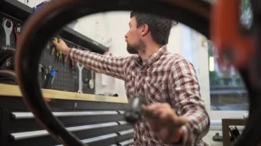 Bisiklet tamircisi, bisiklet atölyesinde tekerlek ve çakıl bisikletinin merkezini tamir ediyor. Bisiklet tamircisinde çalışan bisikletçi çakıl merkezini tamir ediyor. Bisiklet onarımı, servis ve bakım. 